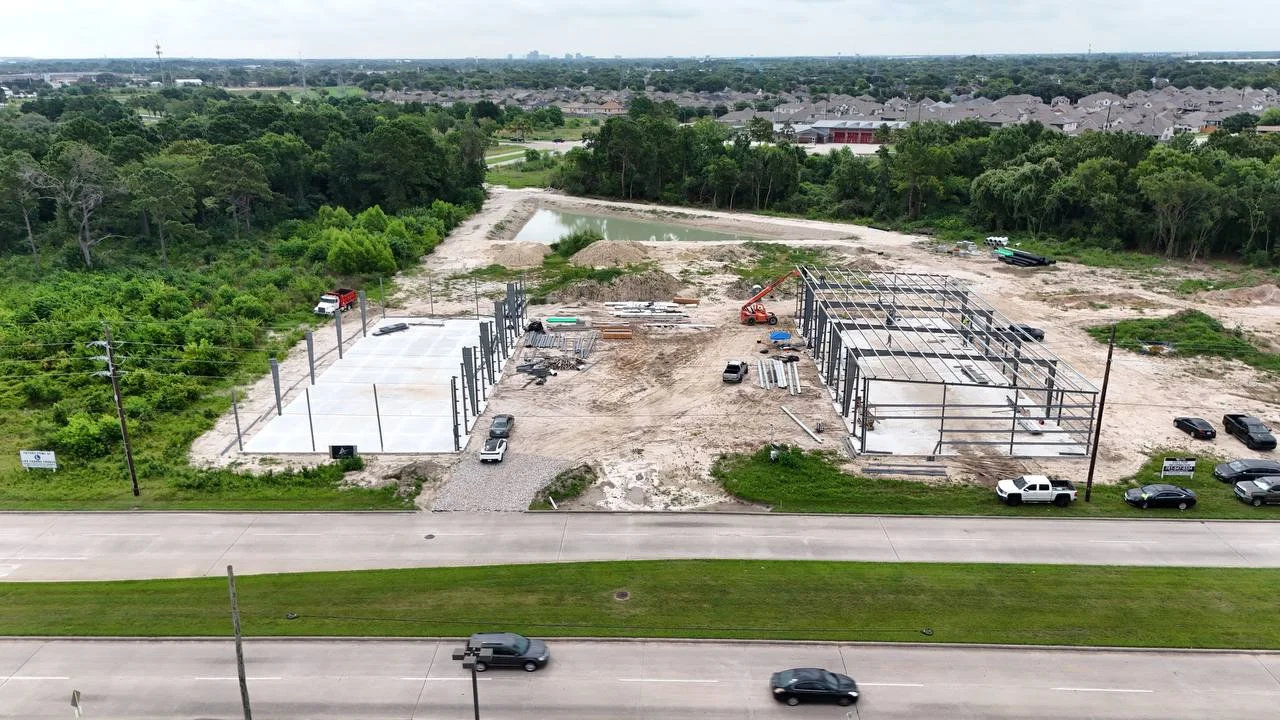 Day 129: PEMB structural steel erection underway — Phase 1 framing rising over both cast slabs, first building's steel frame up, 8 July 2026