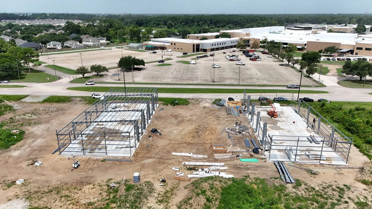 Day 137: PEMB structural steel frames erected on both cast slabs — both Phase 1 buildings framed with columns and rafters up, girts and sheeting to follow, 16 July 2026